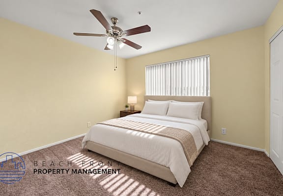 A bedroom with a bed, carpet, and a ceiling fan.