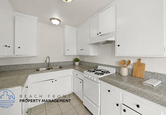 A kitchen with white cabinets and a granite countertop.
