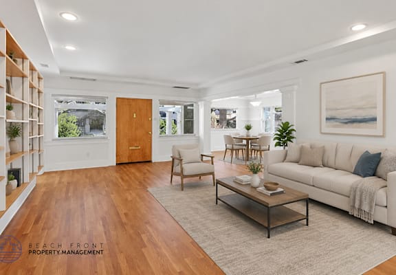 A living room with a white couch, wooden coffee table, and a painting on the wall.