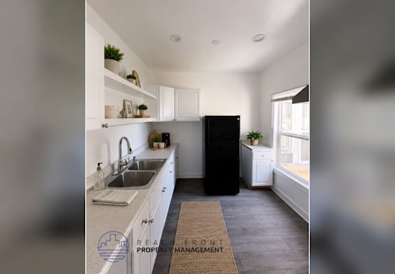 A kitchen with a sink, a refrigerator, and a window.