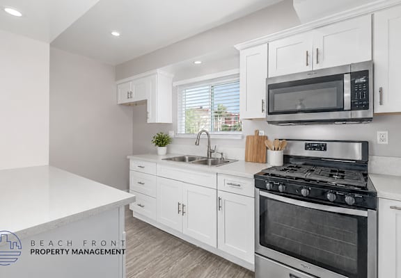 A kitchen with white cabinets and a stove top oven.