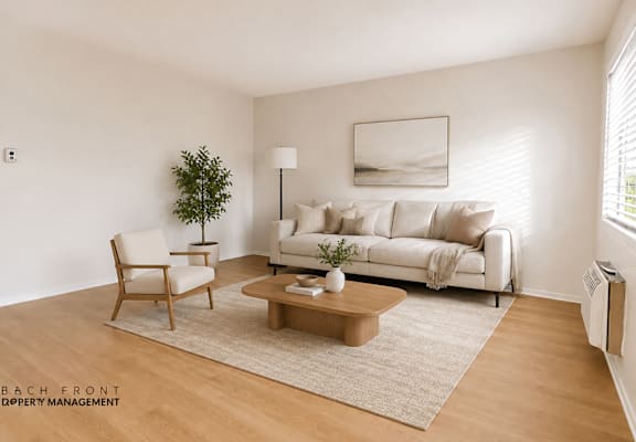 A living room with a white couch, a wooden chair, a coffee table, and a plant.