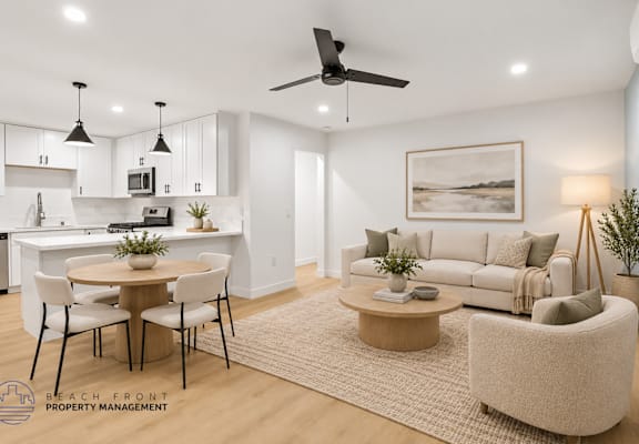 A well-lit, modern living room with a dining area and kitchen in the background.