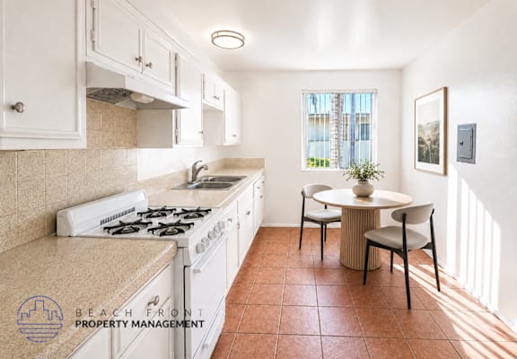 A kitchen with a stove top oven and a dining table with chairs.