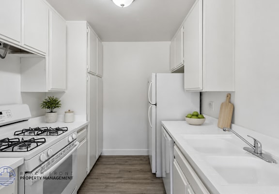 A white kitchen with a stove, sink, and refrigerator.