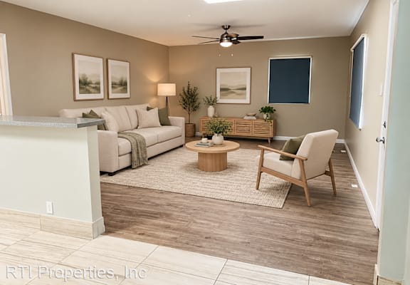 A living room with a white couch, a wooden coffee table, and a ceiling fan.