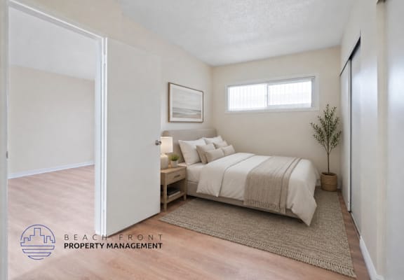 A bedroom with a bed, nightstand, and a plant.