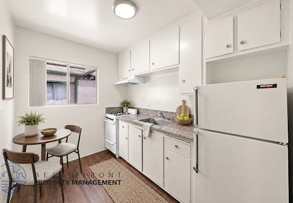 A kitchen with white cabinets and a refrigerator.