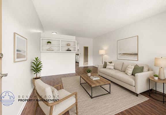 A living room with a white couch, a chair, a coffee table, and a plant.