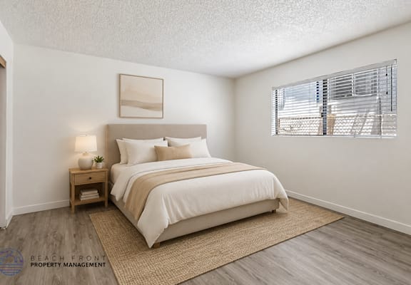 A bedroom with a large bed, a nightstand with a lamp, and a window with blinds.