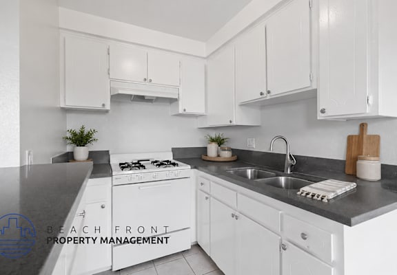 A kitchen with white cabinets and a black countertop.