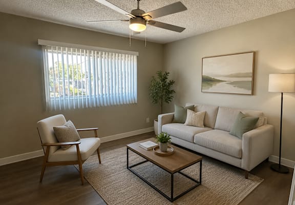 A living room with a white couch, a chair, a coffee table, and a ceiling fan.