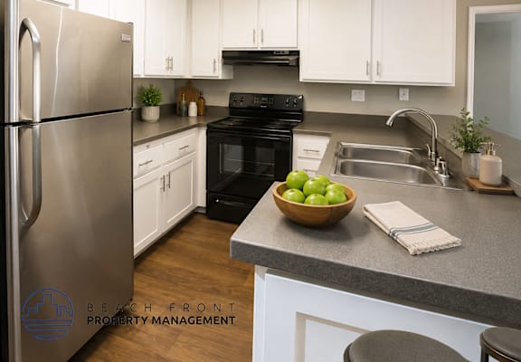 A kitchen with a refrigerator, oven, and sink.