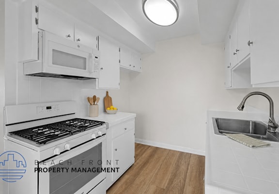 A kitchen with white cabinets and a black stove top oven.