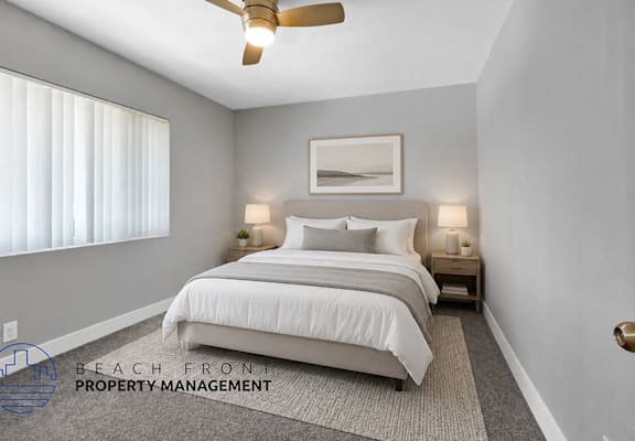 A well-lit bedroom with a large bed and a ceiling fan.