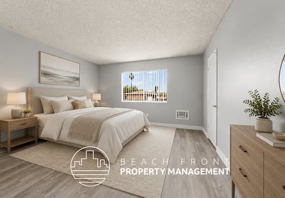 A bedroom with a large bed and a view of the beach through the window.