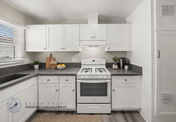 A kitchen with white cabinets and a stove top oven.