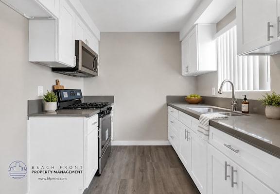 A kitchen with white cabinets and a black stove top.