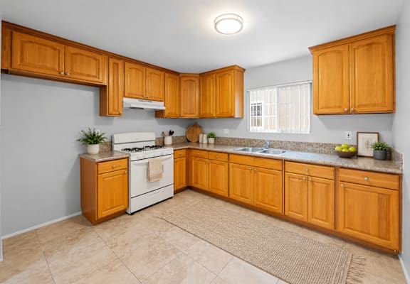 A kitchen with wooden cabinets and a white stove top oven.