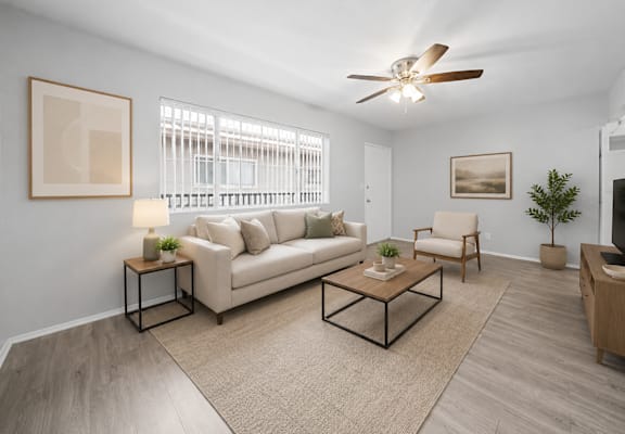 A living room with a beige couch, a coffee table, and a ceiling fan.
