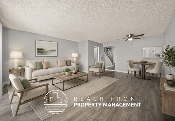 A living room with a staircase in the background and a logo for Beach Front Property Management.