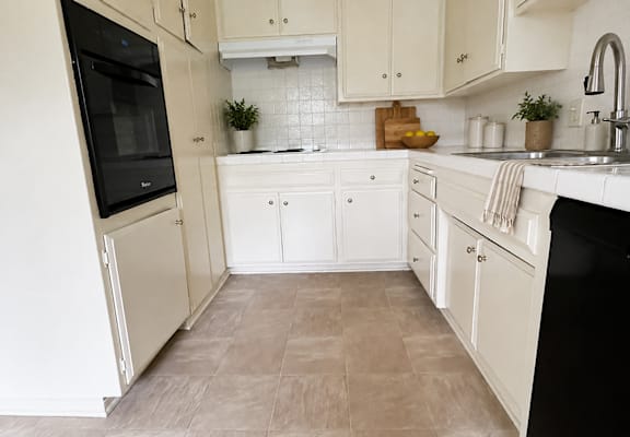 A kitchen with white cabinets and a black fridge.
