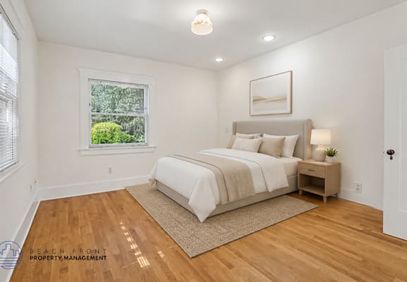 A bedroom with a large bed and a window overlooking a green area.