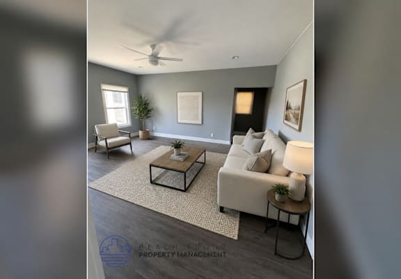 A living room with a white couch, a coffee table, and a ceiling fan.