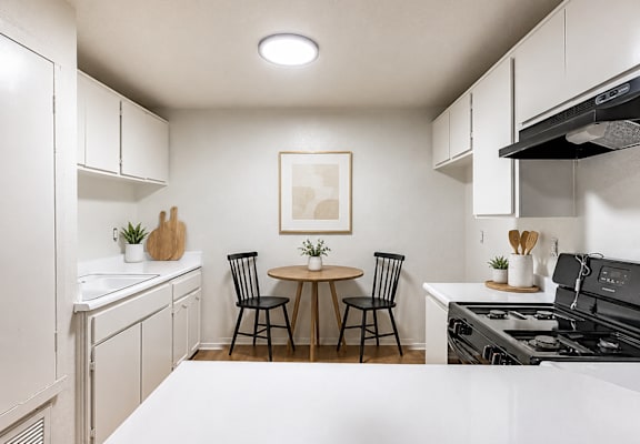 A kitchen with a table and chairs in the middle.