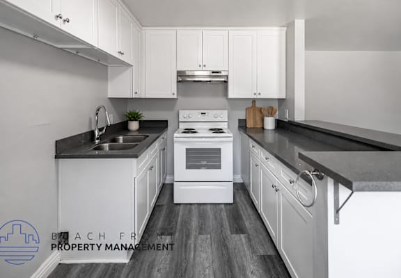 A modern kitchen with white cabinets and a black countertop.
