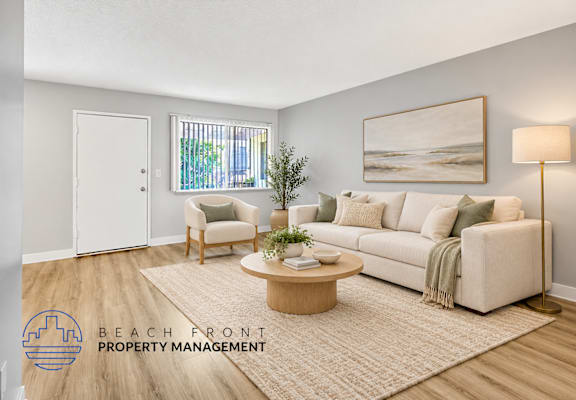A living room with a white couch, a wooden coffee table, and a painting on the wall.