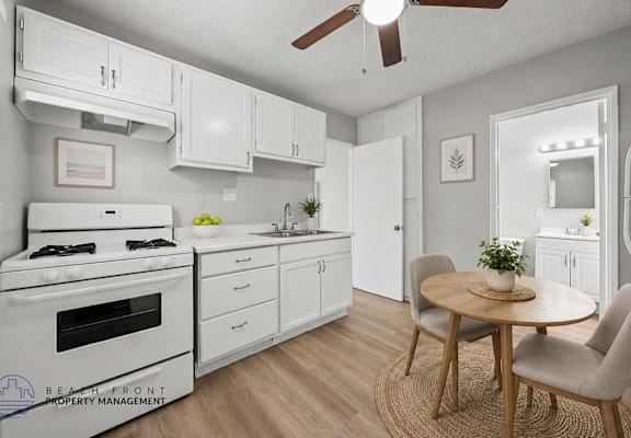 A kitchen with a white stove, cabinets, and a ceiling fan.