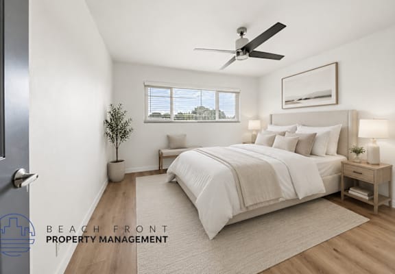 A well-lit bedroom with a large bed and a ceiling fan.