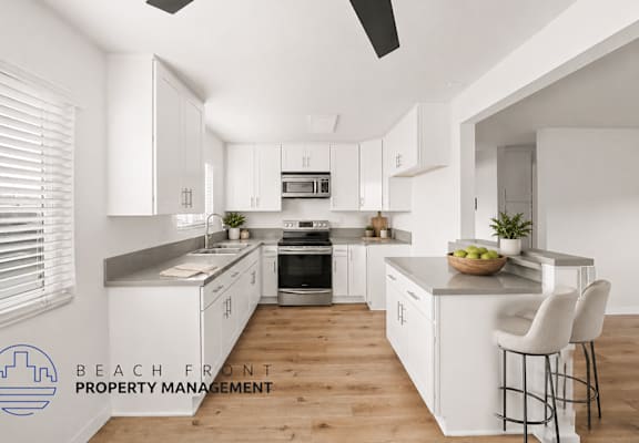 A modern kitchen with white cabinets and a wooden floor.