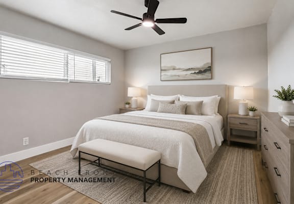 A well-lit bedroom with a large bed, a bench, and a ceiling fan.