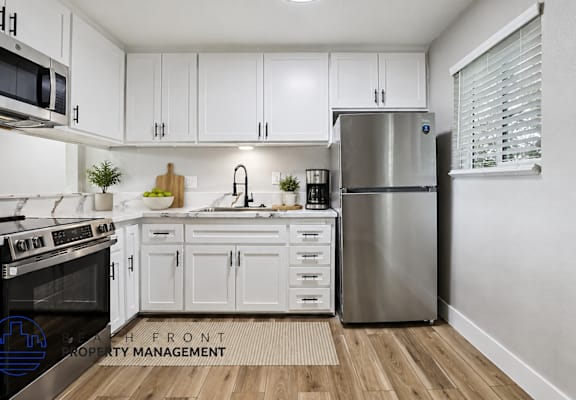 A modern kitchen with white cabinets and stainless steel appliances.