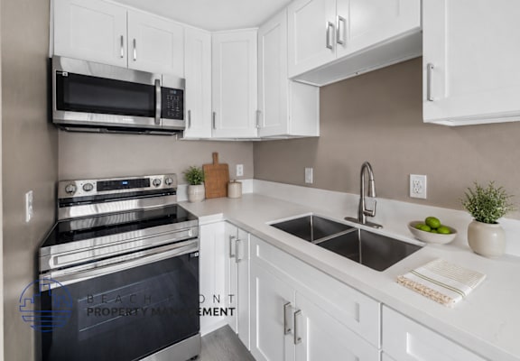 A modern kitchen with white cabinets and a black stove top oven.