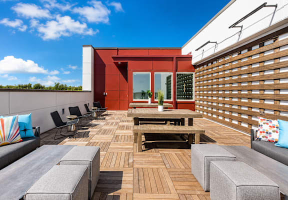 A wooden deck with a bench and chairs.