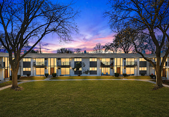 A building with a lawn in front and trees on the sides.