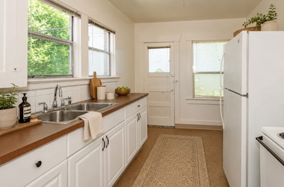 A kitchen with white cabinets and a white fridge.
