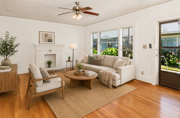 A living room with a fireplace, a sofa, a chair, a coffee table, and a potted plant.