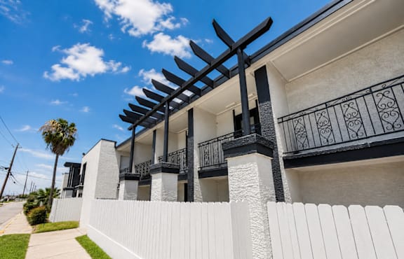 A white building with a black railing and a black pergola.