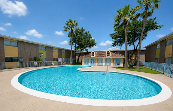 A round swimming pool in front of a building with a fence around it.