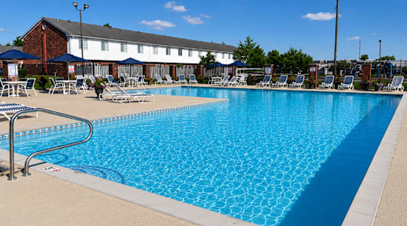 A large swimming pool with a metal railing and sun loungers.