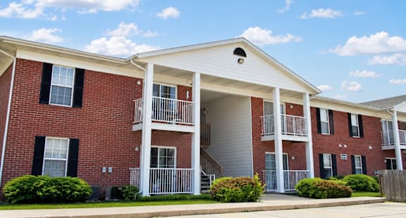 A red brick apartment building with a white roof and a balcony.