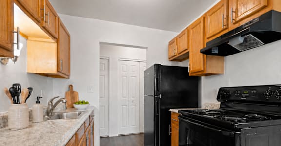 A kitchen with black appliances and wooden cabinets.