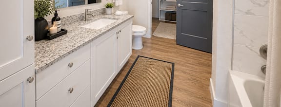 Modern bathroom featuring a spacious vanity, oversized mirror, and contemporary fixtures at The Mill Old Town Apartments.