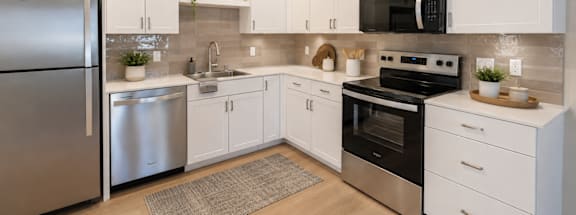 A modern kitchen with white cabinets and stainless steel appliances.