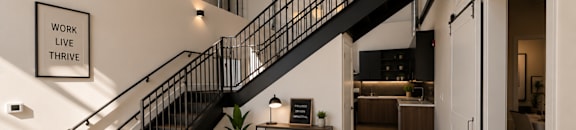 A black metal staircase with a white wall and a sign that says "work live thrive".