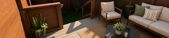 A wooden deck with a white couch and a table with a plant on it.